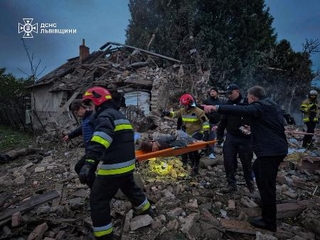 　ロシアの無人機とミサイルによる攻撃で破壊された住宅のがれきの上で、負傷者を搬送する救助隊員ら＝５日、ウクライナ西部リビウ州（ウクライナ非常事態庁提供・ロイター＝共同）