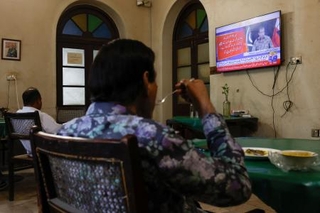 　パキスタン軍の記者会見を報じるテレビを見る人たち＝１０日、パキスタン南部カラチ（ロイター＝共同）