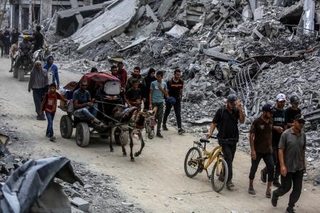 　停戦合意発効を受け、自宅に戻るため破壊された建物の間を移動するパレスチナ人ら＝１２日、ガザ南部ハンユニス（ゲッティ＝共同）