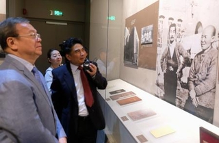 　内山完造と魯迅が写った写真（右）を眺める上海市人民対外友好協会の関係者ら＝１９日、中国上海市（共同）