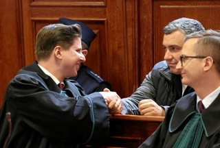 　ドイツへの移送を認めない裁判所の判断を受け、弁護士と握手する「ノルドストリーム」破壊事件の容疑者（右奥）＝１７日、ワルシャワ（ロイター＝共同）