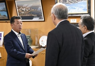 　北海道泊村議会の議長らから意見書を受け取る高橋鉄徳村長（左）＝３１日午前、北海道泊村