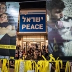 　１２日、イスラエル・テルアビブの広場で、拘束中の人質の写真を見つめる女性（ゲッティ＝共同）