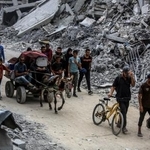 　停戦合意発効を受け、自宅に戻るため破壊された建物の間を移動するパレスチナ人ら＝１２日、ガザ南部ハンユニス（ゲッティ＝共同）