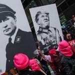 　ナチスの制服姿で描いたトランプ米大統領（右）とロシアのプーチン大統領のプラカードを掲げ、「ＮＯ　ＫＩＮＧＳ（王はいらない）」デモに参加した人たち＝米ニューヨーク（ロイター＝共同）