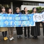 　東京地裁による被選挙権年齢引き下げ訴訟判決を受け「不当判決」などと書かれた紙を掲げる原告団＝２４日午後、東京・霞が関