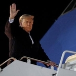 　２４日、米大統領専用機に乗り込む前に手を上げるトランプ大統領＝ワシントン郊外（ロイター＝共同）