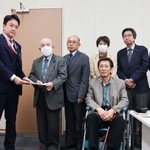 　警察庁の担当者に要請文を手渡す「犯罪被害補償を求める会」の藤本護代表理事（左から２人目）＝２９日午前、国会