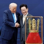 　韓国・慶州で、トランプ米大統領（左）に「天馬塚金冠」のレプリカを贈呈し握手する李在明大統領＝２９日（聯合＝共同）