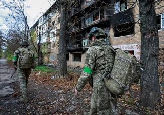 　１日、ウクライナ東部ドネツク州の前線で、ロシア軍の攻撃を受けた建物の周辺を歩くウクライナ兵（ロイター＝共同）