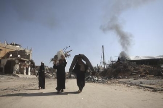 　ガザ南部ハンユニスで破壊された自宅から回収した衣類や毛布を運ぶパレスチナ人＝１８日（ゲッティ＝共同）