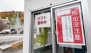 　大倉山ジャンプ競技場（左奥）の近くに掲示された「熊出没注意」のポスター＝２日、札幌市