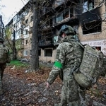 　１日、ウクライナ東部ドネツク州の前線で、ロシア軍の攻撃を受けた建物の周辺を歩くウクライナ兵（ロイター＝共同）