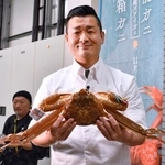 　４５０万円で落札した石川県のブランドガニ「輝」を手にする旅館関係者＝６日夜、金沢市