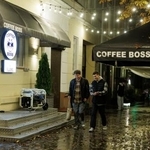 　ウクライナ北部チェルニヒウで、停電中に発電機を使って営業するカフェの前を歩く若者＝１０月（ロイター＝共同）