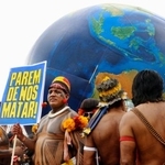 　熱帯林保護などを訴え、「私たちを殺すのをやめろ」と書かれたプラカードを掲げる先住民男性＝１５日、ブラジル・ベレン（共同）