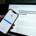 　フェイスブックのログイン画面と、新たなメタの方針が映し出されたモニター＝２０日、オーストラリア・シドニー（ＡＰ＝共同）