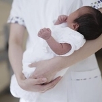 　病院で助産師に抱かれる新生児