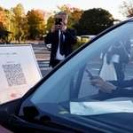 　車中泊避難の実証実験で、スマートフォンを使って受け付けをする参加者＝２２日午後、熊本市