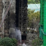 　大規模火災が起きた香港北部の高層住宅に入る捜索隊員ら＝３０日、香港北部・新界地区大埔（共同）