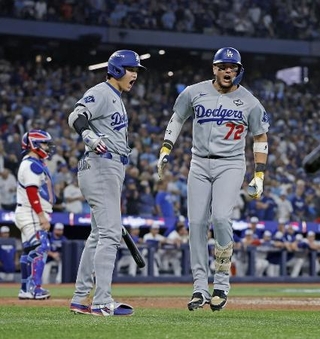 　ブルージェイズ戦の９回、同点ソロを放ったロハス（右）を迎えるドジャース・大谷＝２０２５年１１月、トロント（共同）