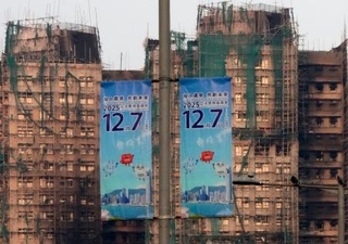 　火災のあった高層住宅群（奥）の近くに掲げられた立法会選挙の投票を呼びかけるポスター＝５日、香港（共同）