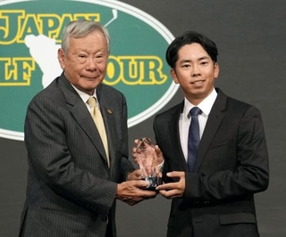 　日本ゴルフツアー機構の諸星裕会長（左）から、オールアラウンドランキング賞のトロフィーを受け取る生源寺龍憲＝８日、東京都港区