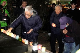 　不戦を誓う集会で、献灯する参加者＝８日午後、長崎市