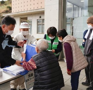 　市営住宅などへの入居に向けて、避難所で必要な物資を受け取る被災者（手前）＝１２日午前、大分市佐賀関