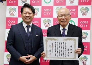 　奈良県御所市役所で山田秀士市長（左）から感謝状を受け取った西辺豊彦さん＝１２日午後