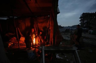　イスラエル軍の攻撃で破壊された跡で、たき火で暖をとる人たち＝１２日、ガザ（ＡＰ＝共同）