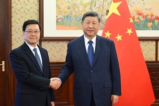 　香港政府トップの李家超行政長官（左）と握手する中国の習近平国家主席＝１６日、北京の中南海（新華社＝共同）