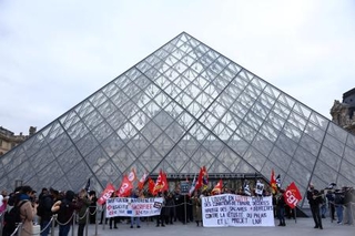 　ルーブル美術館入り口の「ピラミッド」前で待遇改善などを訴える職員ら＝１７日、パリ（ロイター＝共同）