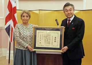 　表彰状を持つマクドナルド昭子さん（左）と鈴木浩駐英国大使＝１９日、ロンドン（共同）