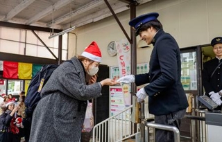 　水間鉄道開業１００周年の記念切符を受け取る乗客（左）＝２４日午前、大阪府貝塚市の貝塚駅