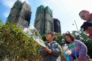 　火災があった高層住宅群の近くで花を手向ける子ども＝２５日、香港（共同）