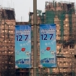 　火災のあった高層住宅群（奥）の近くに掲げられた立法会選挙の投票を呼びかけるポスター＝５日、香港（共同）