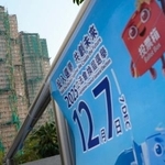 　火災のあった高層住宅群（左奥）の近くに掲示された立法会選挙の投票を呼びかけるポスター＝５日、香港（共同）