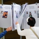 　立法会選挙の投票所で、候補者の情報がまとめられたファイルを見る有権者＝７日、香港（共同）