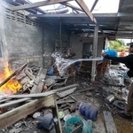 　火災が起きた家屋に水をかけるタイの警察官＝１１日、タイ・スリン県（ＡＰ＝共同）