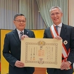 　オスロの日本大使公邸で開かれた叙勲伝達式で、杉山明大使（左）から勲記を手渡されたノルウェーのストルテンベルグ財務相＝１２日（共同）