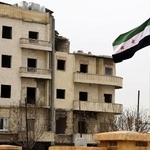 　内戦で破壊された建物前に掲げられた新たなシリア国旗＝６日、北部アレッポ