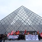　ルーブル美術館入り口の「ピラミッド」前で待遇改善などを訴える職員ら＝１７日、パリ（ロイター＝共同）
