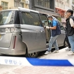 　香港の強盗事件で、近くの路上に残された容疑者が使ったとみられる車を調べる警察官ら＝１８日（共同）