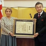 　表彰状を持つマクドナルド昭子さん（左）と鈴木浩駐英国大使＝１９日、ロンドン（共同）