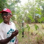 　パッションフルーツのつるを手に農場の説明をするフィーリョさん＝１１月、ブラジル・モスケイロ島（共同）