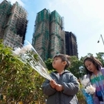 　火災があった高層住宅群の近くで花を手向ける子ども＝２５日、香港（共同）