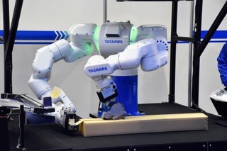 　人の両腕の動きを模倣し梱包作業をする安川電機のロボット＝２０２５年１２月、東京都江東区