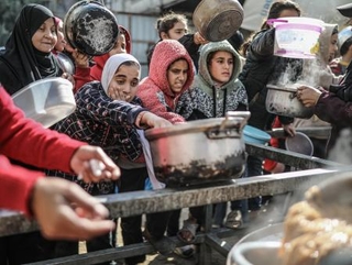 　１４日、パレスチナ自治区ガザ中部で、配給の食事を受け取るパレスチナ人（ゲッティ＝共同）