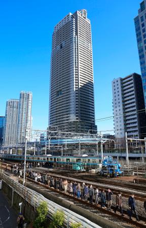 　新橋-浜松町間で停車したＪＲ京浜東北線の車両から降りて線路を歩く乗客＝１６日午前１０時４分、東京都港区